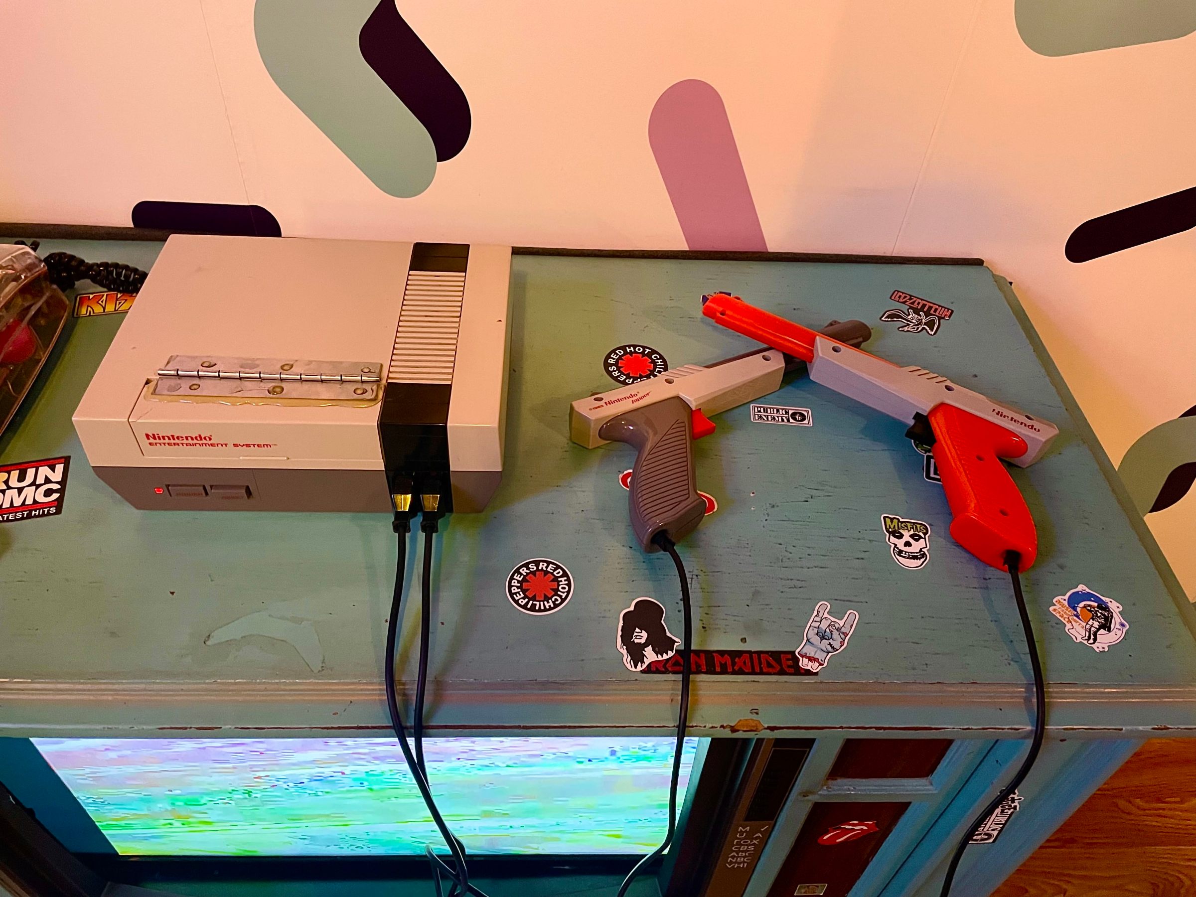 Retro Nintendo console and two light guns on a blue table with stickers.