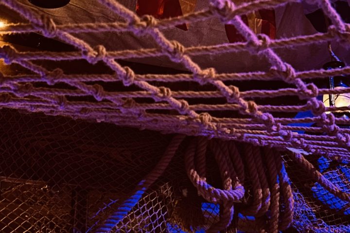 Ropes and nets with dim lantern lighting on a ship's deck.