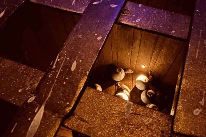 Wooden structure with circular opening revealing spherical objects inside, dimly lit with warm light.