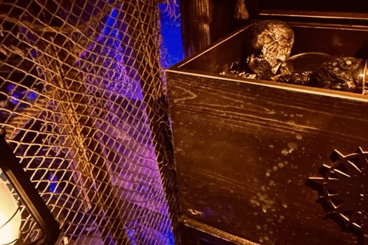 Dimly lit scene with netting, lantern, and wooden crate containing skulls.