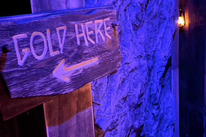 Wooden sign with 'FOLD HERE' and arrow, under purple light.