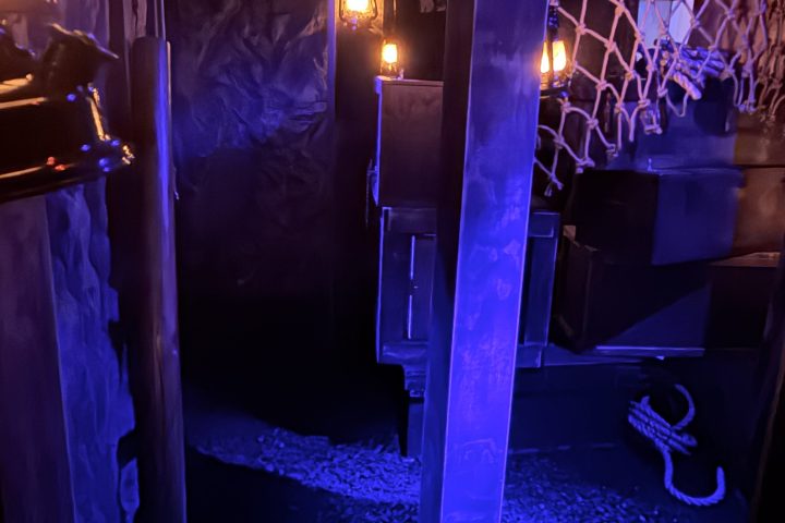 Dimly lit room with netting, blue lighting, and scattered objects.
