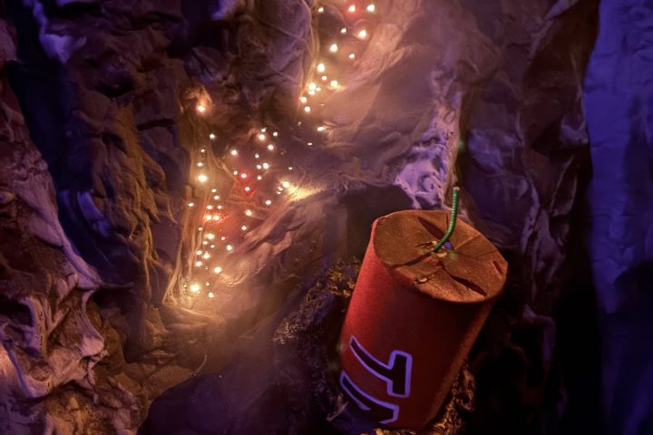 Toy dynamite on rocky surface with glowing lights.