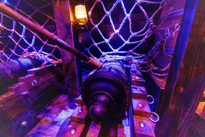 Antique cannon on a wooden ship with ropes and lantern.