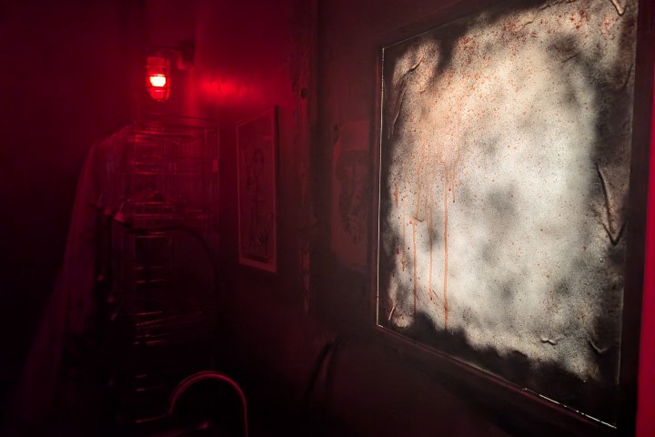 Dimly lit room with red light and eerie, foggy window.