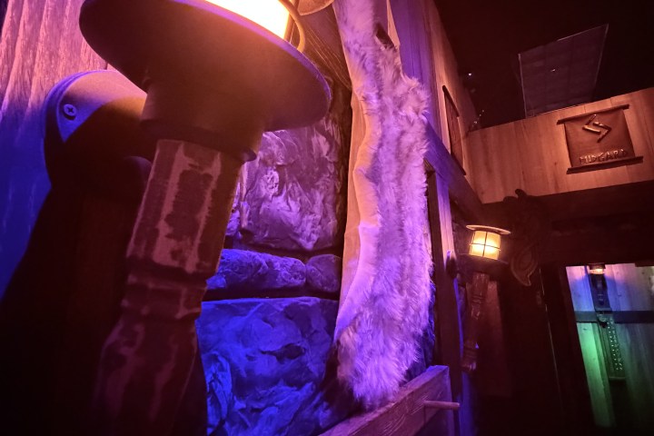 Dimly lit hallway with lanterns, fur pelt, and runes on wooden walls.