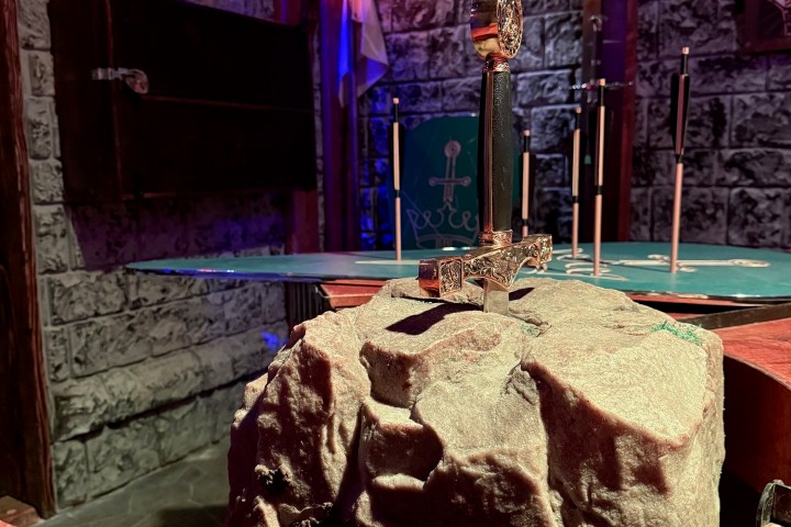 Sword in stone with medieval decor in dimly lit room.