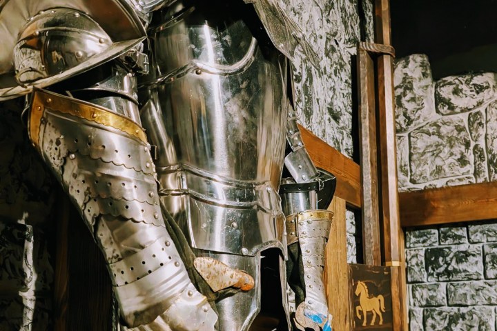Medieval knight armor displayed with stone wall backdrop.