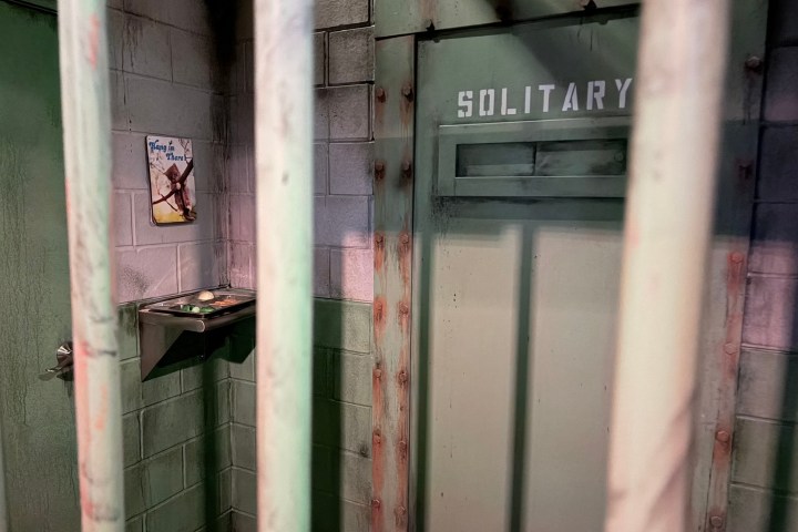 A barred cell with a door labeled 'Solitary' and a small shelf holding items.