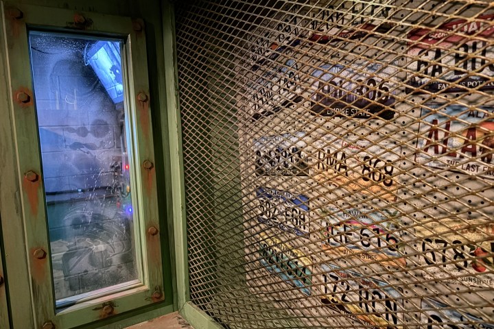 Caged storage area with visible license plates on metal mesh wall.