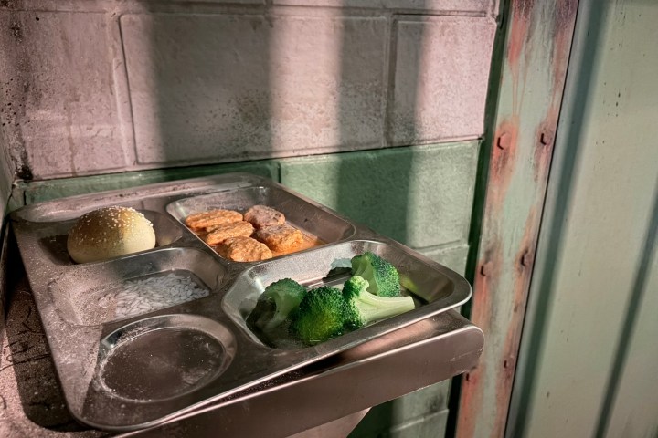 Metal tray with bread, nuggets, broccoli on industrial background.