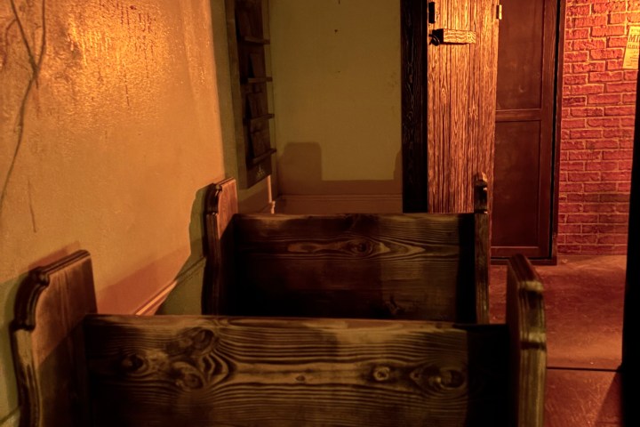 Dimly lit corridor with wooden benches and graffiti on walls