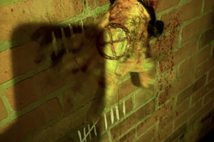 Blurred hand in chains with tally marks on brick wall and symbol on palm.