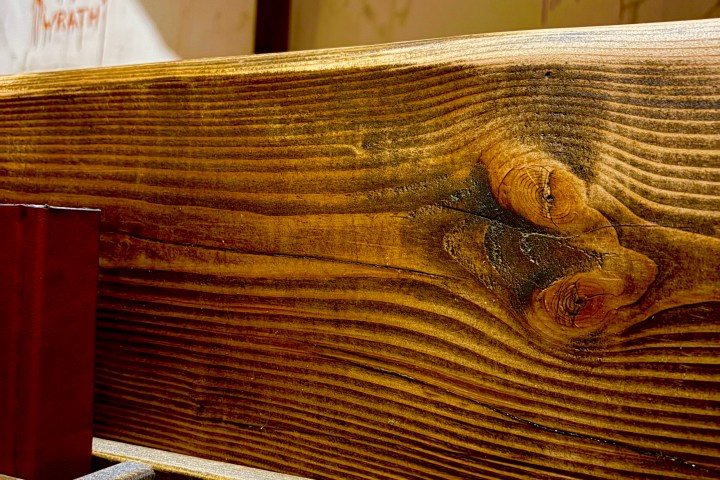 Wooden pew in church with cross and sin symbols on wall.